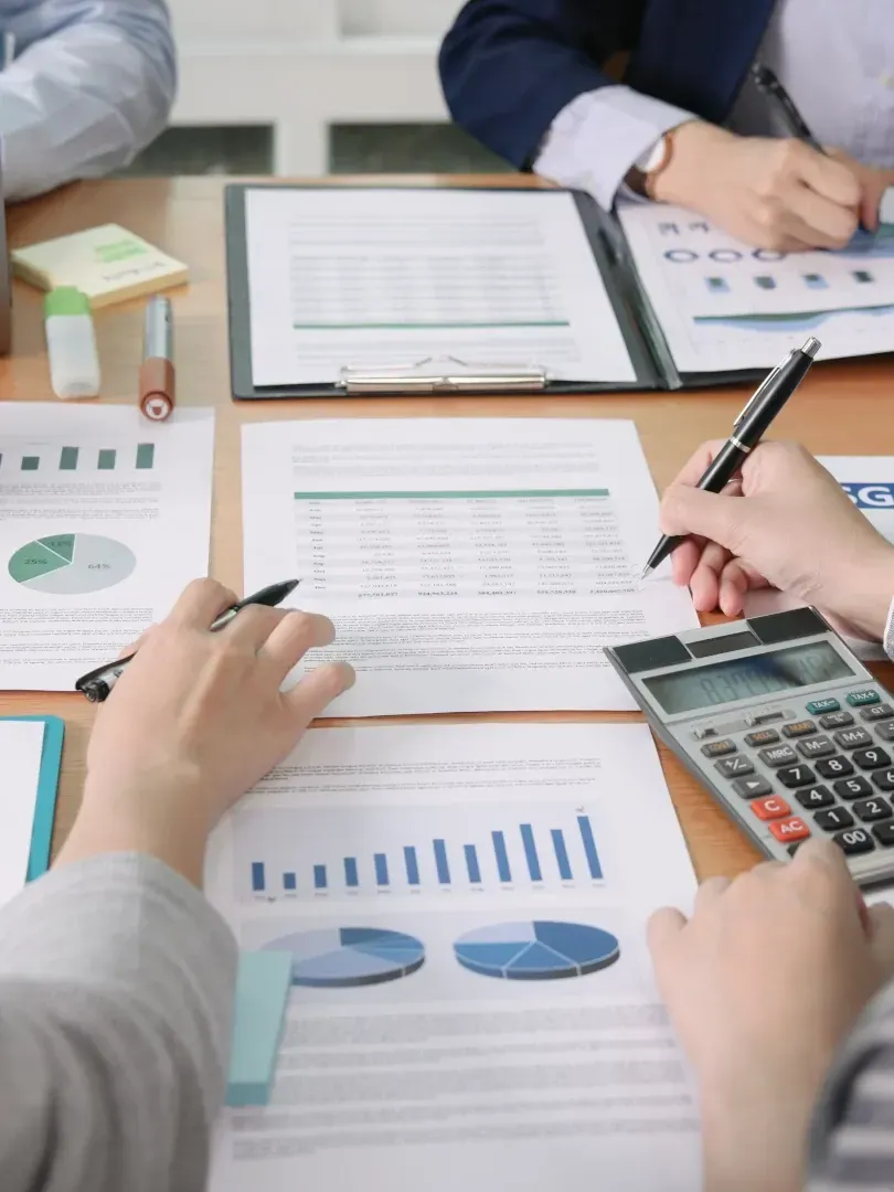 Team reviewing financial reports with charts, calculators, and a laptop at a conference table