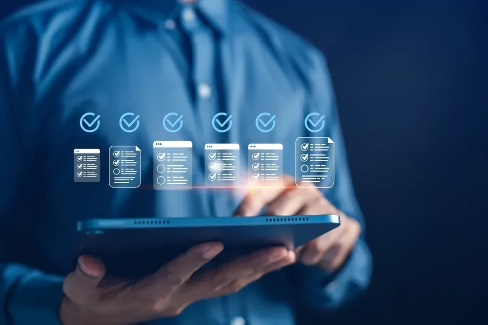Person holding a tablet with glowing digital dashboard icons on a blue background