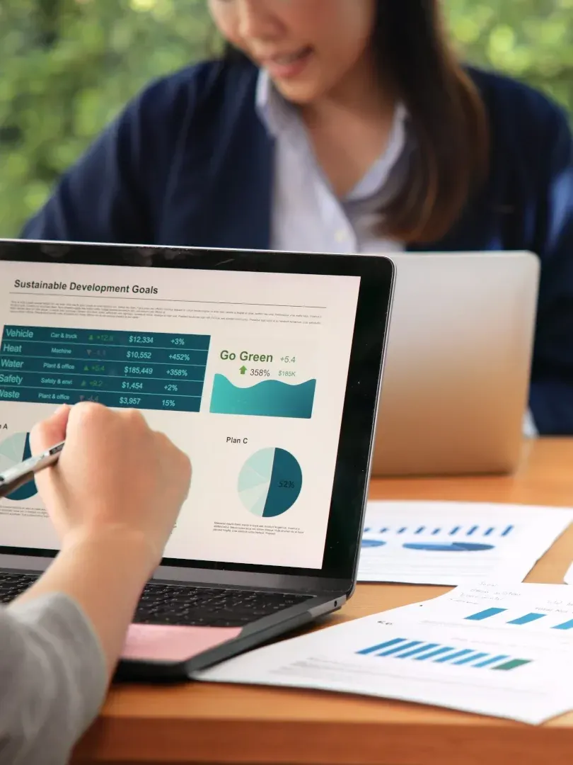 Person pointing at analytics dashboard on laptop with charts and laptop in background
