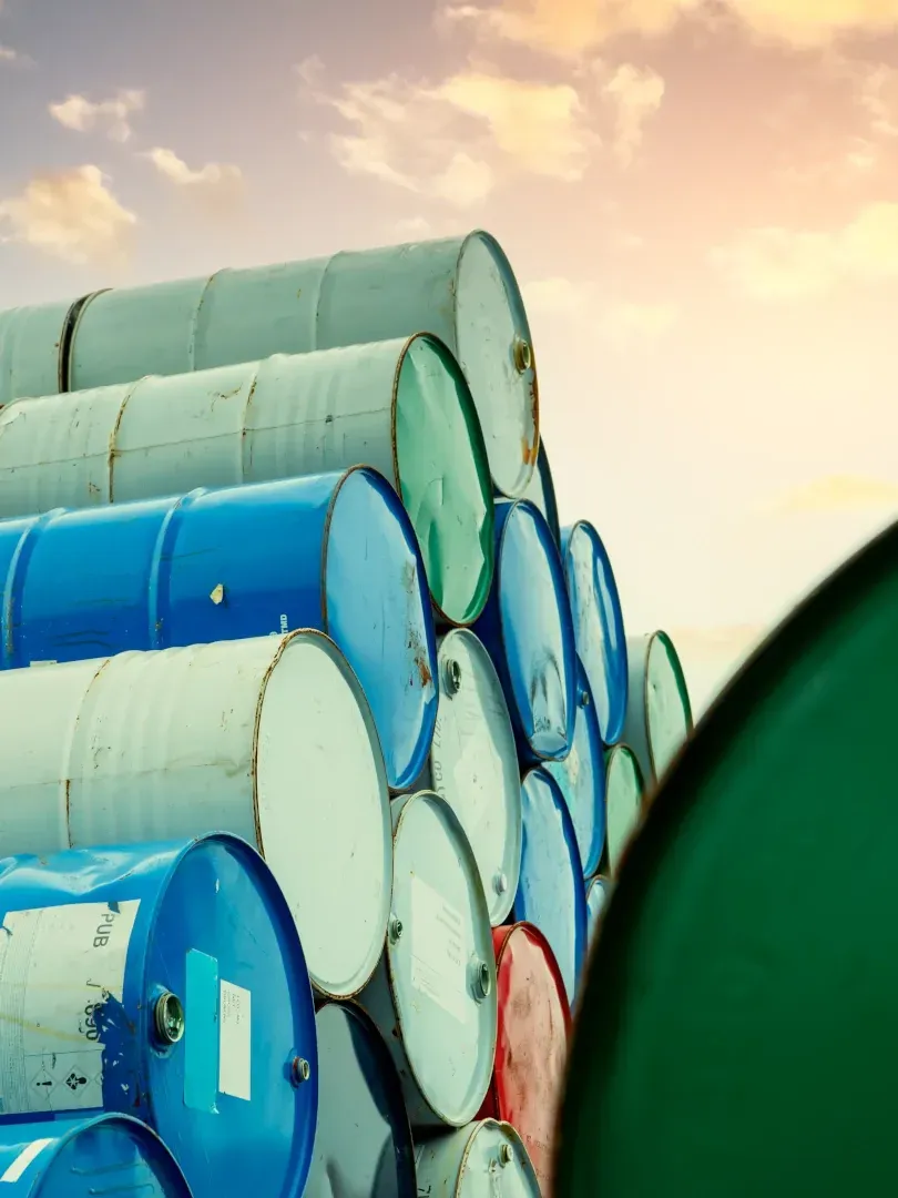 Stacked blue and green industrial drums against a bright sky
