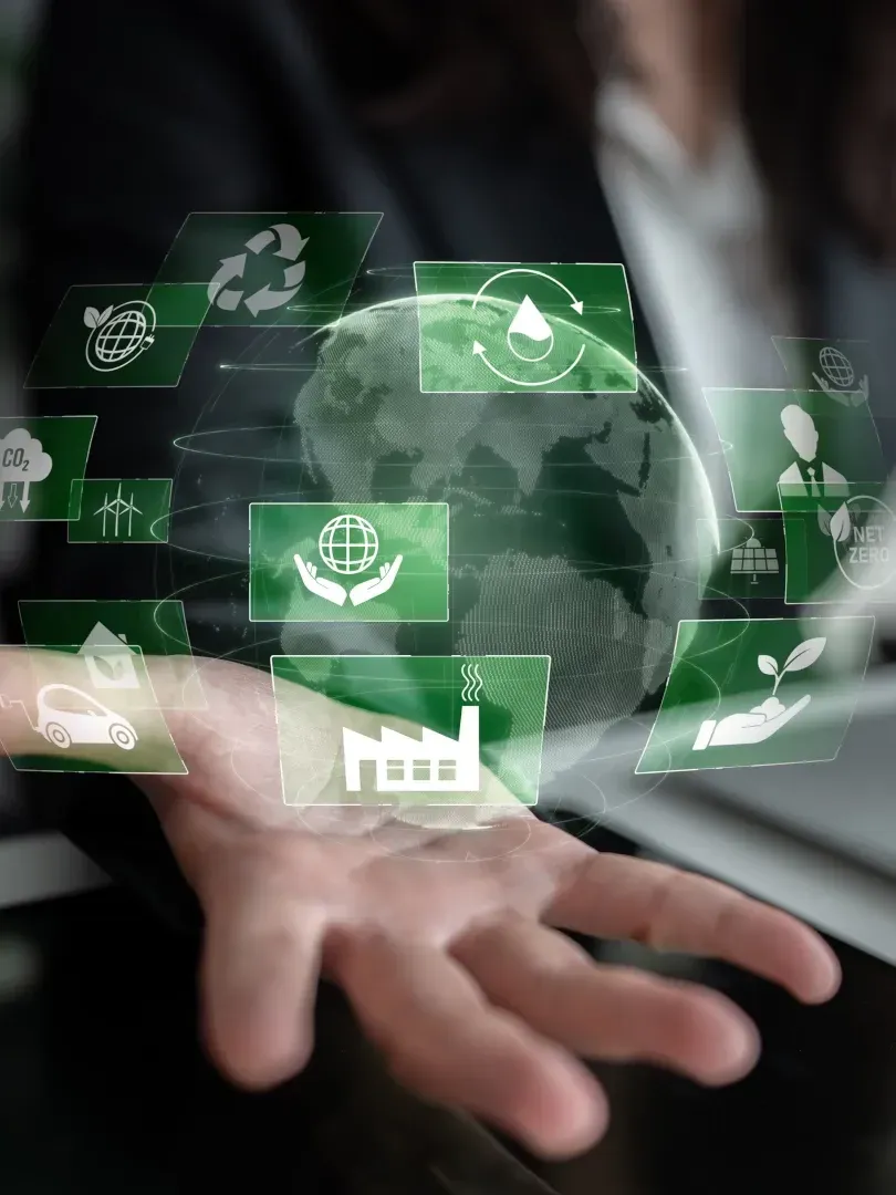 Hand holding a glowing digital globe with green sustainability icons floating around it
