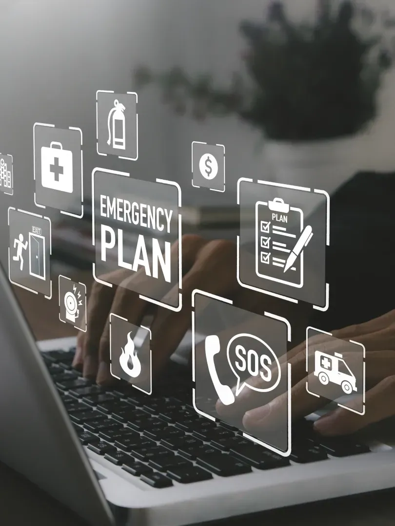 Hands typing on laptop with digital emergency plan icons and SOS symbol floating above screen