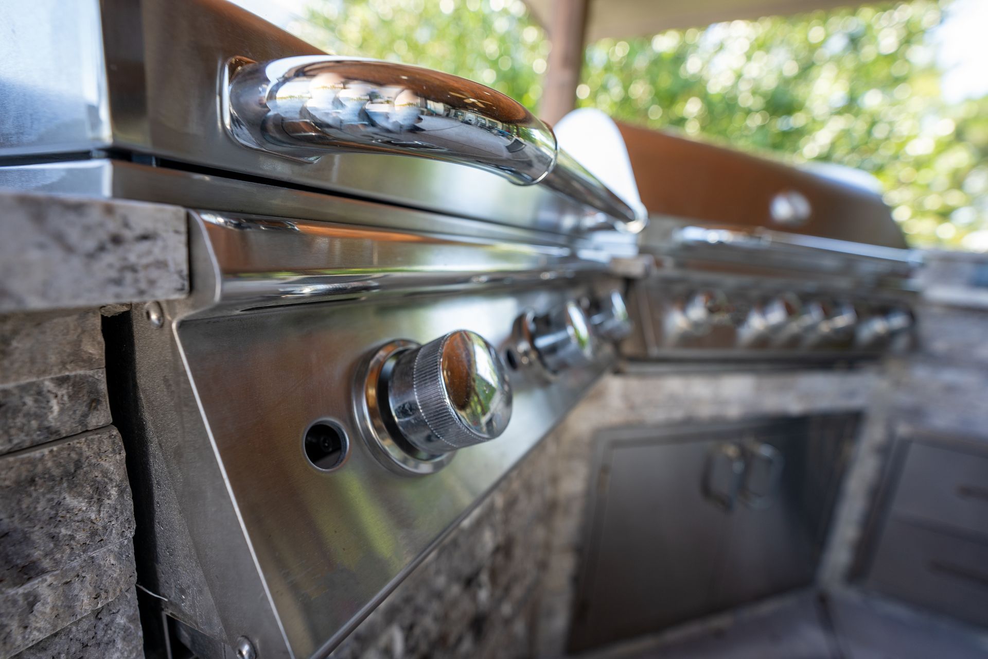 A close up of a stainless steel grill in an outdoor kitchen.