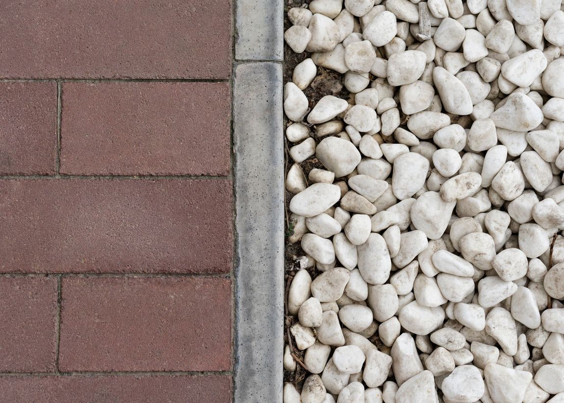 A close up of bricks and gravel on a sidewalk.