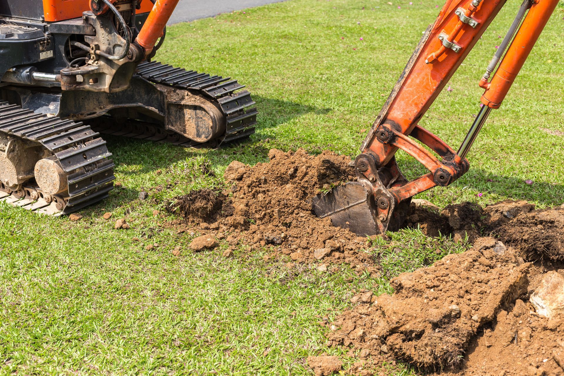 A bulldozer is digging a hole in the grass.