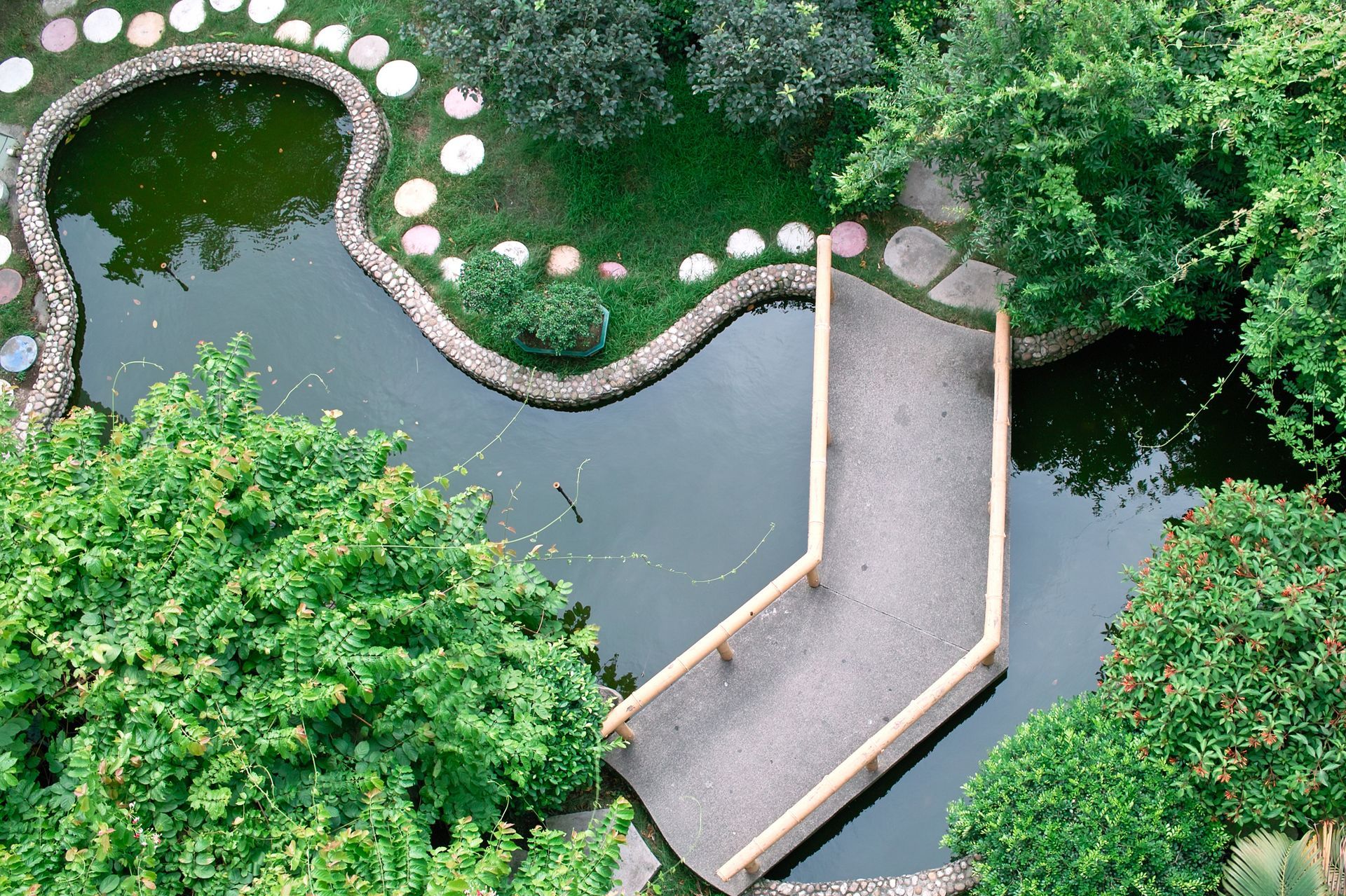 An aerial view of a pond with a bridge over it