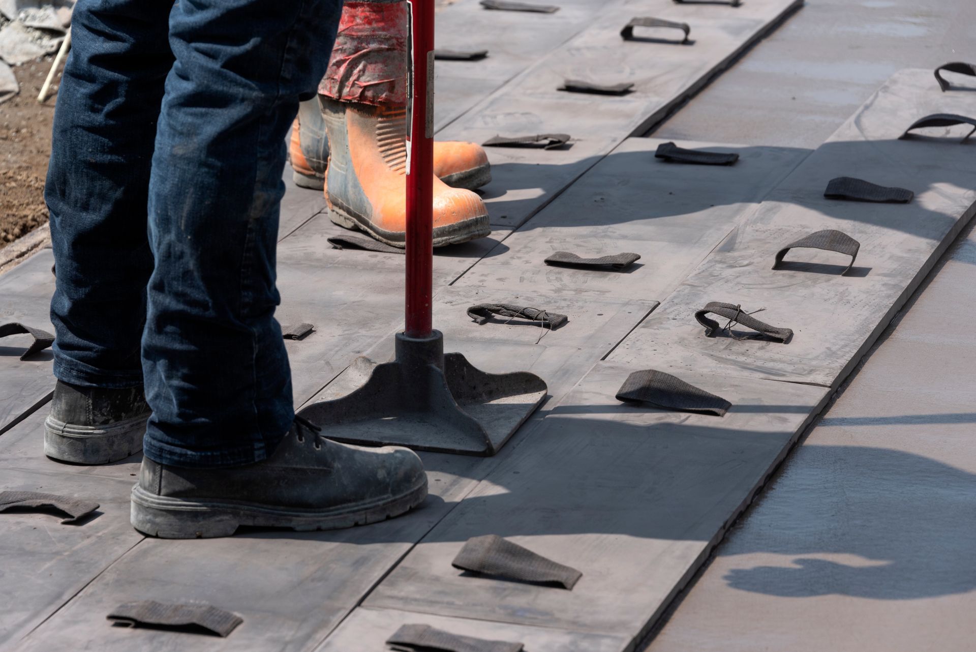 A person is standing on a concrete surface with a broom.