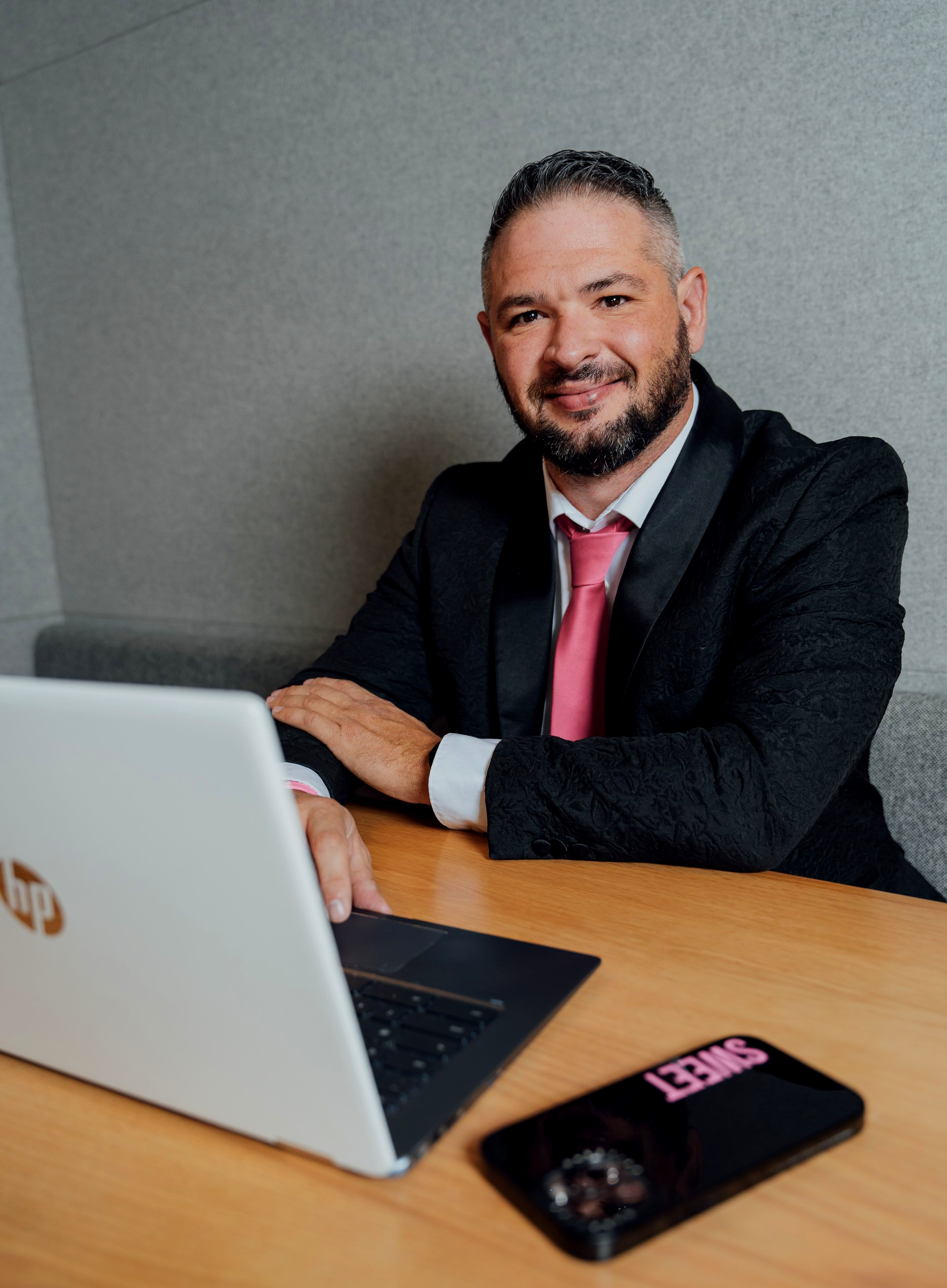 A man in a suit and tie is sitting at a table with a laptop.