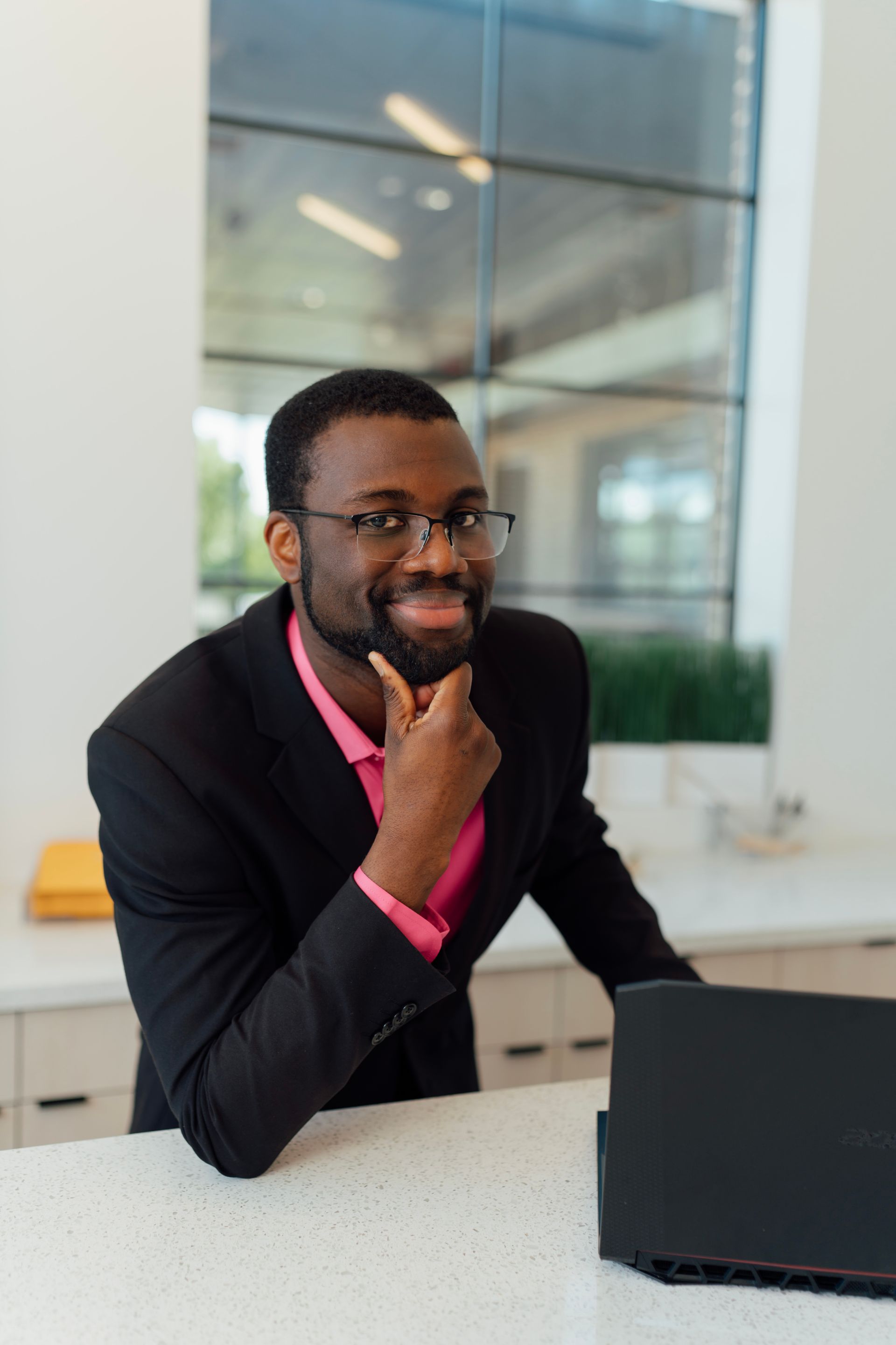 A man in a suit and pink shirt is smiling for the camera.