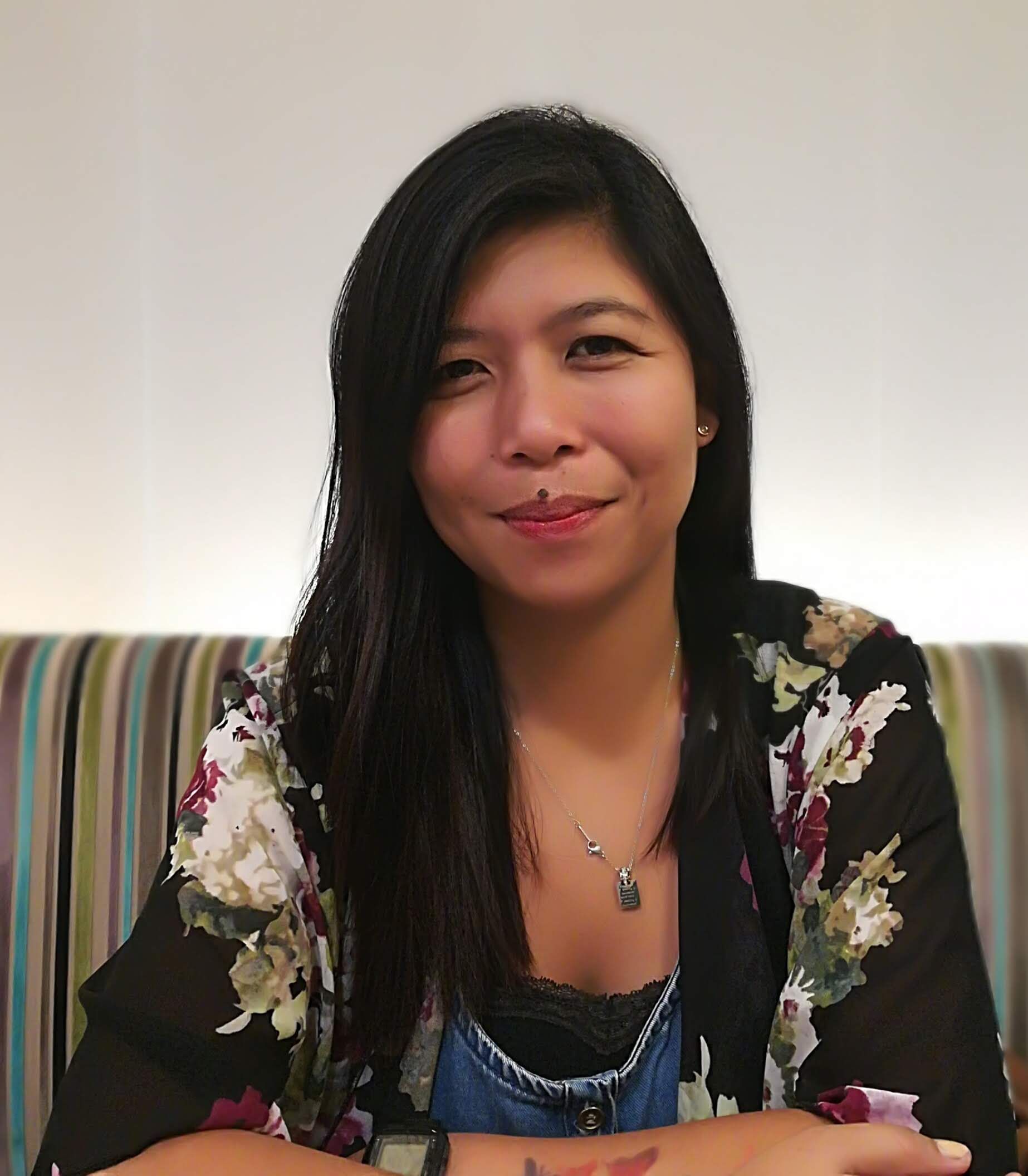A woman is sitting on a couch wearing a floral jacket