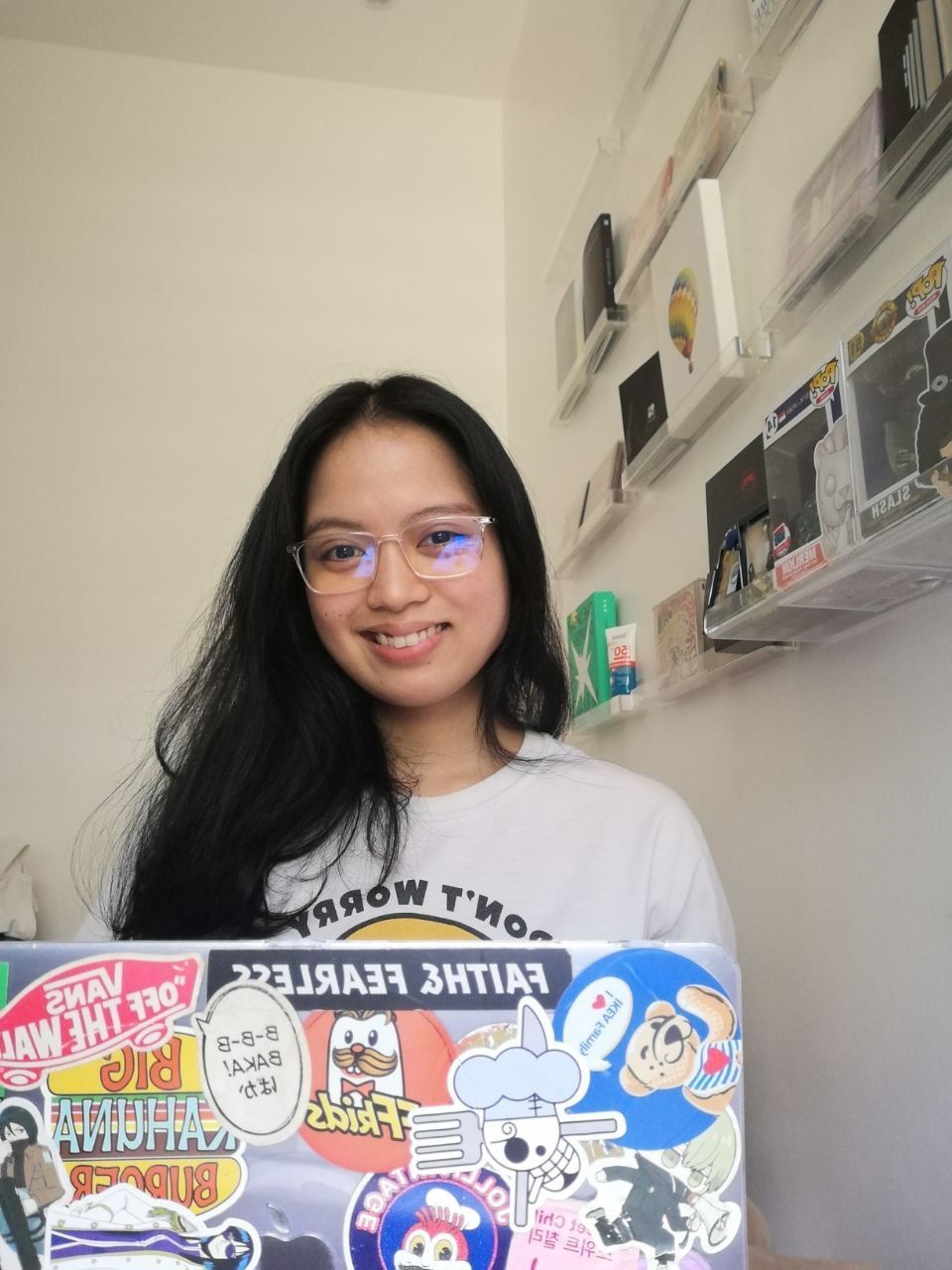 A woman is holding a laptop with stickers on it