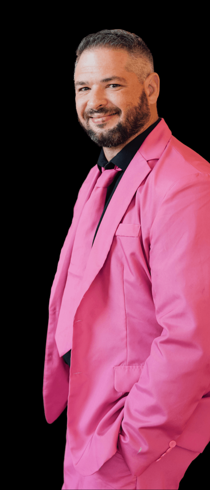 a man wearing a pink suit and tie with his hands in his pockets