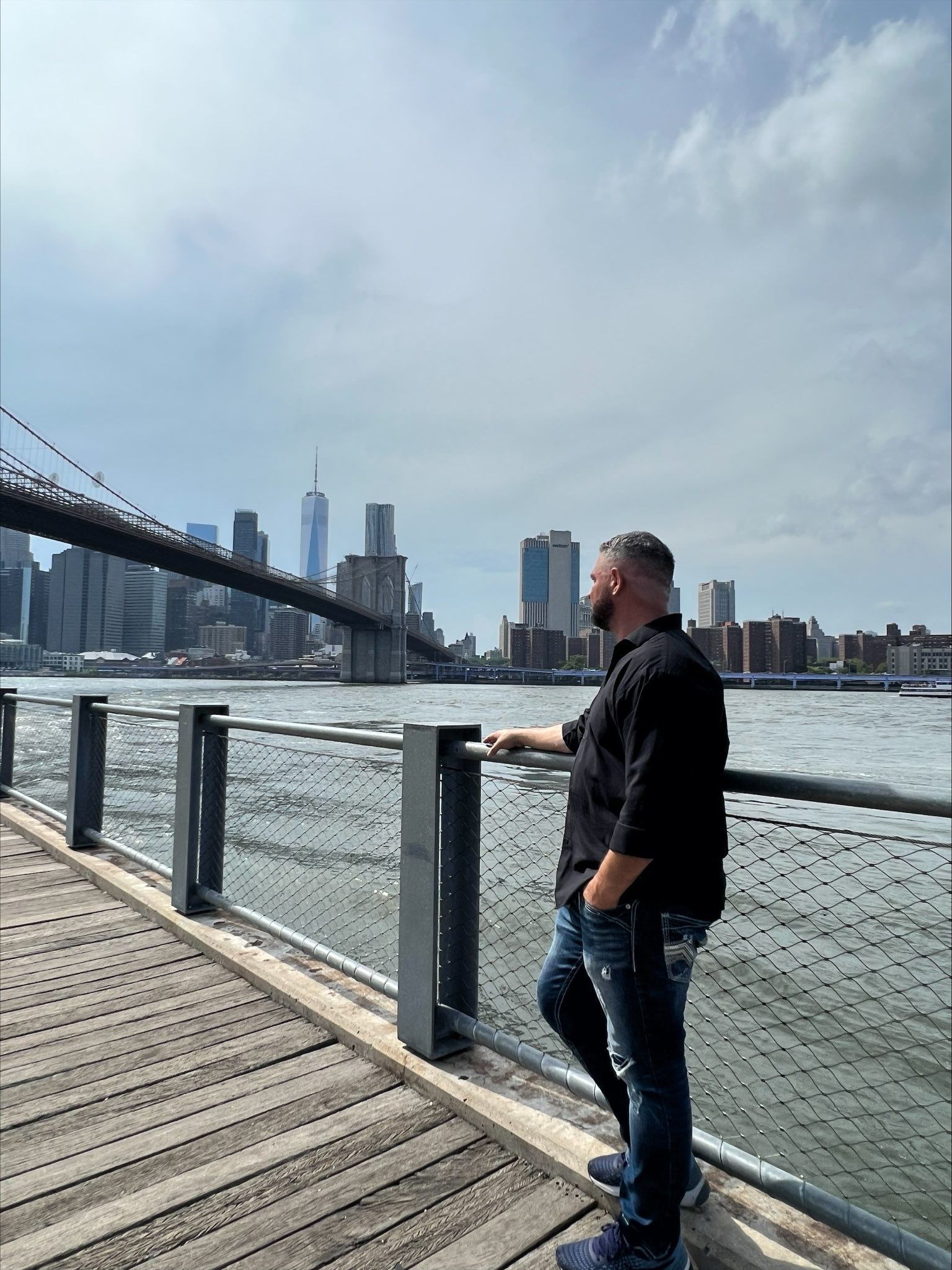 A man is standing on a pier overlooking a body of water.