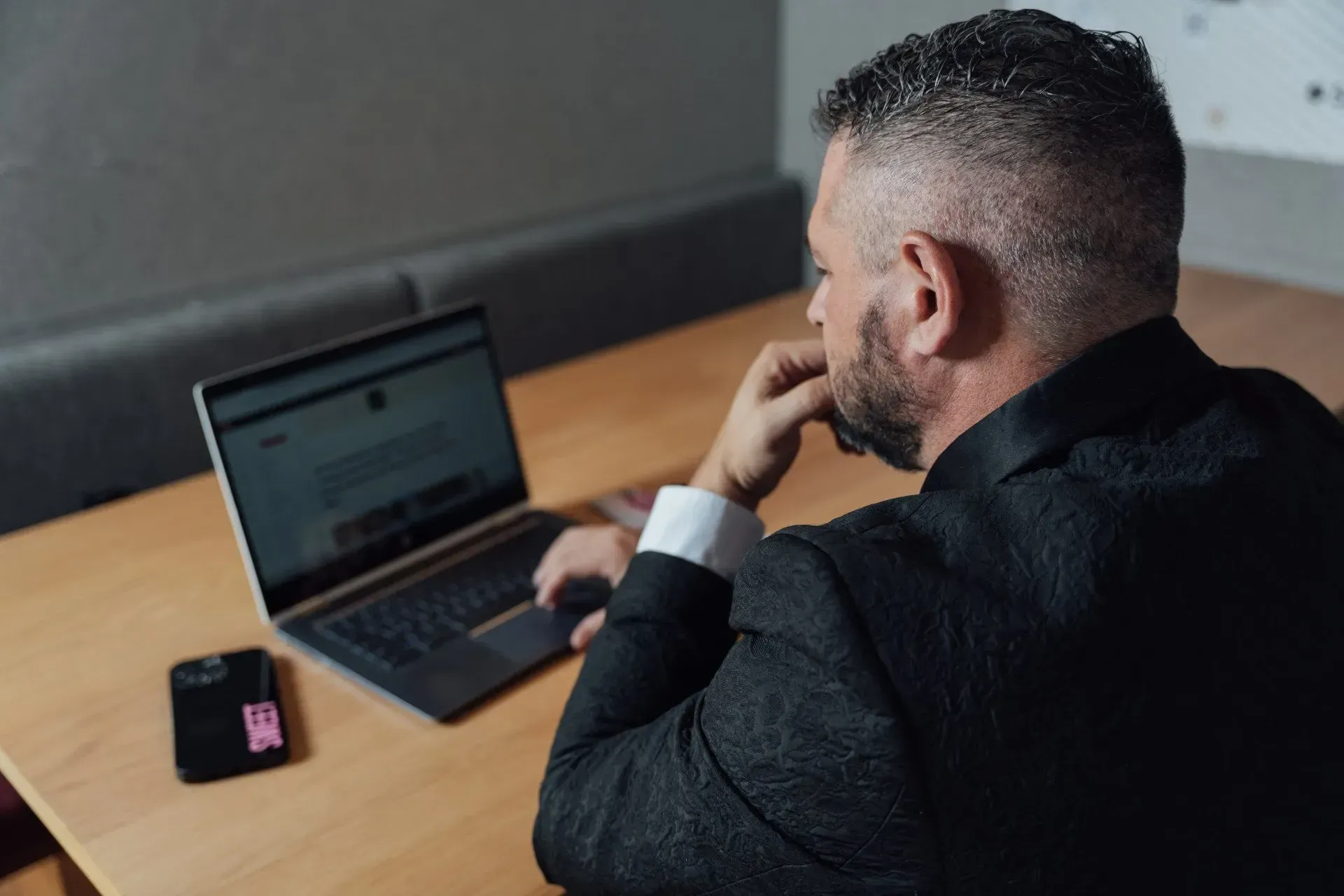 A man in a suit and tie is leaning against a wall.