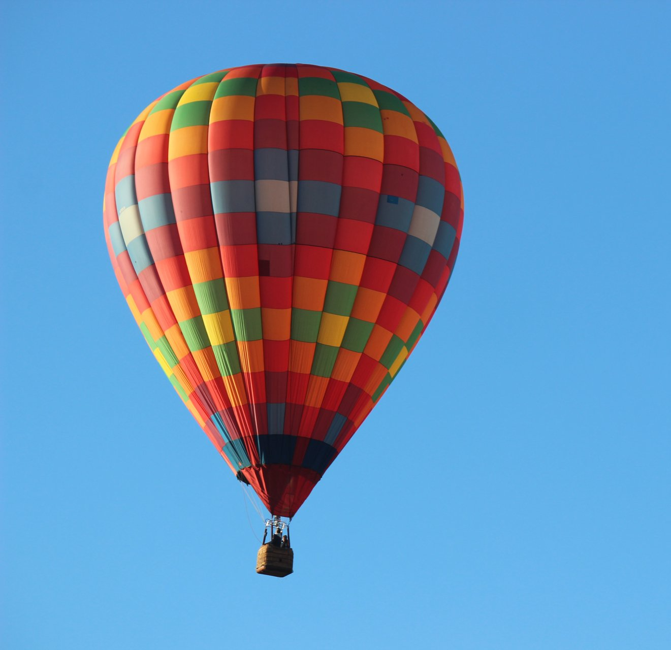 A colorful hot air balloon is flying in the blue sky