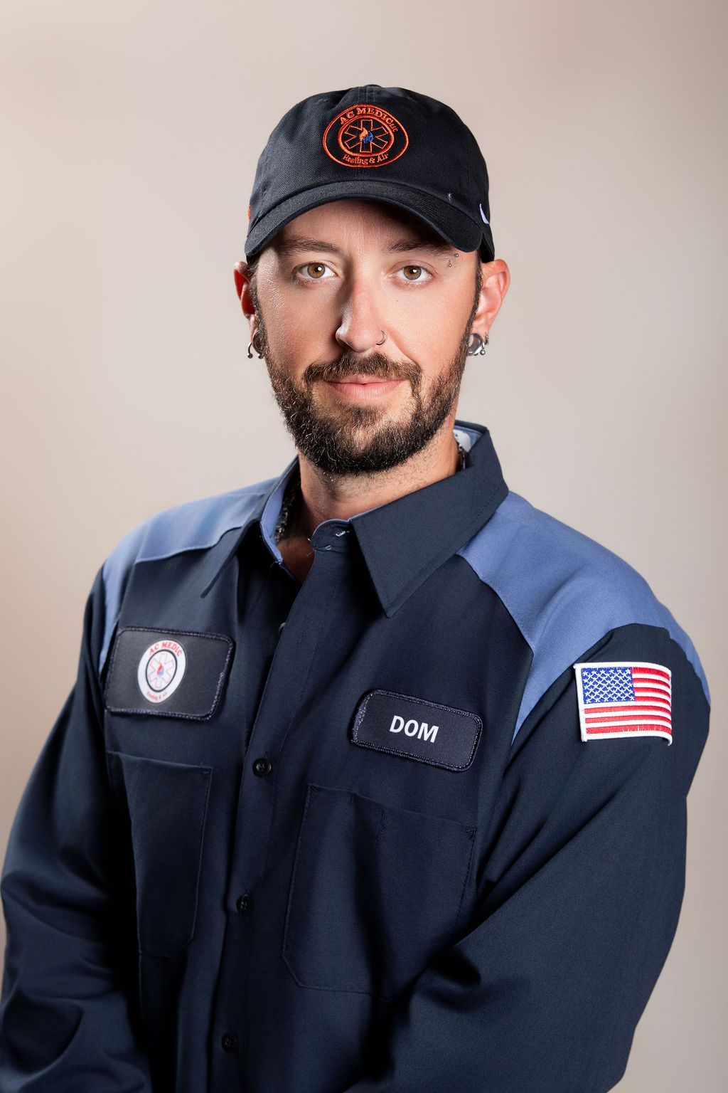 Uniformed firefighter in navy shirt and cap, standing with a neutral expression against a plain background.