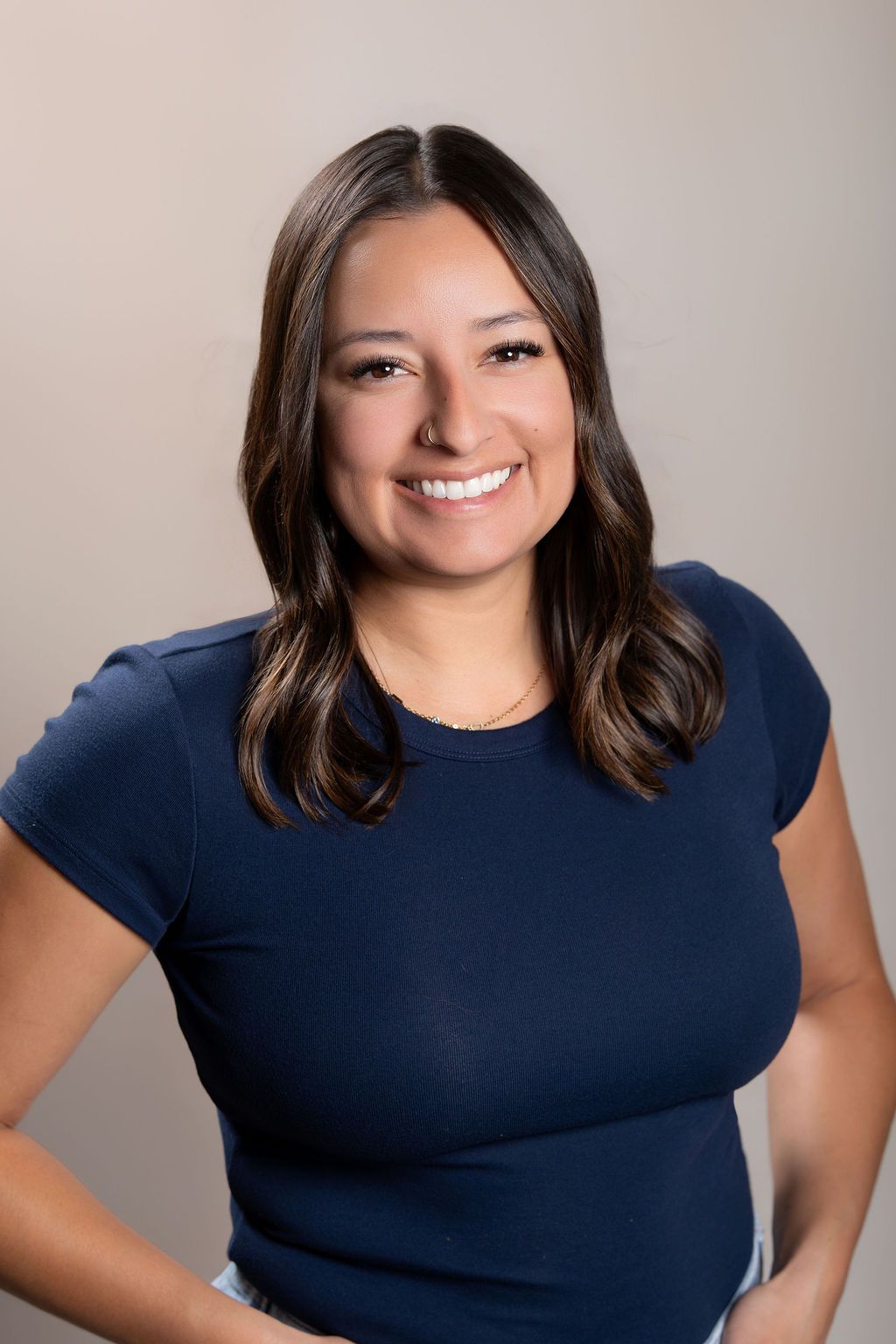 Smiling woman in a navy shirt posing against a neutral background