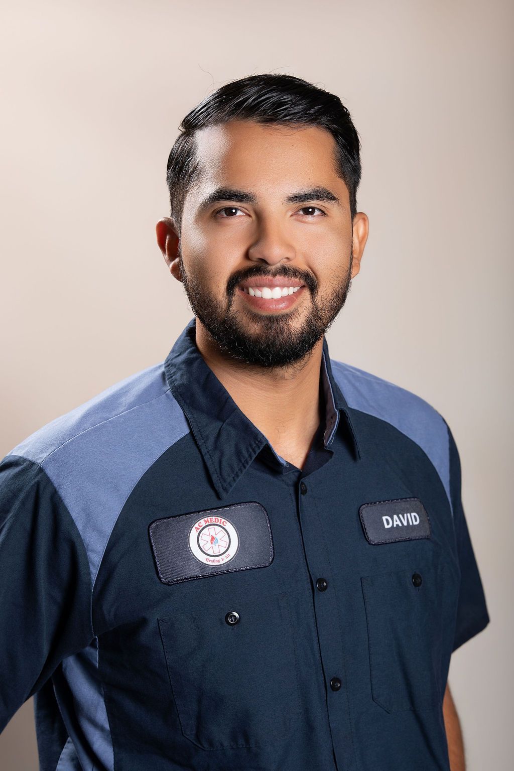 Man in a navy work shirt smiling against a neutral studio background