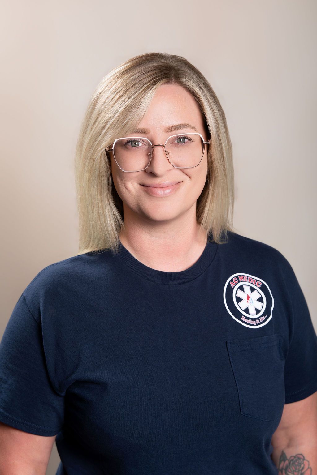 Smiling person with glasses in a navy T-shirt against a neutral background