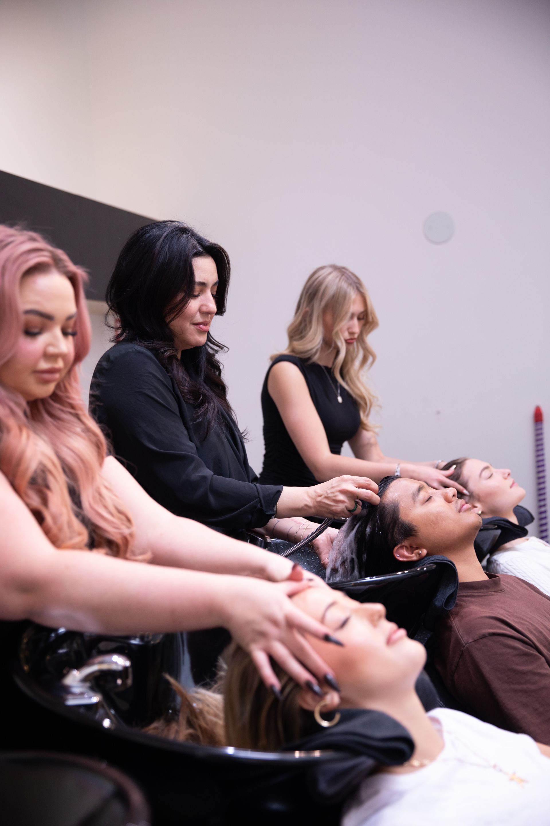 People getting shampoo and scalp massages at salon sinks