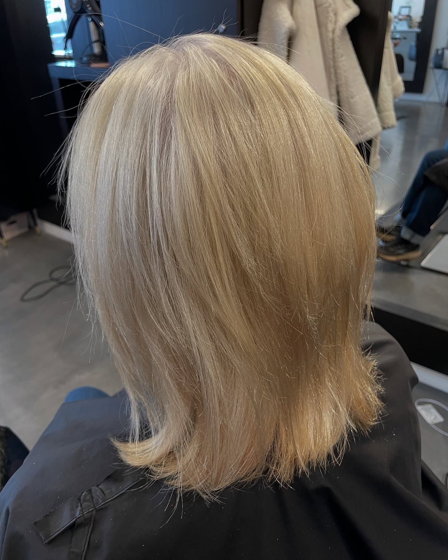 Blonde shoulder-length haircut with soft layers in a salon chair, back view