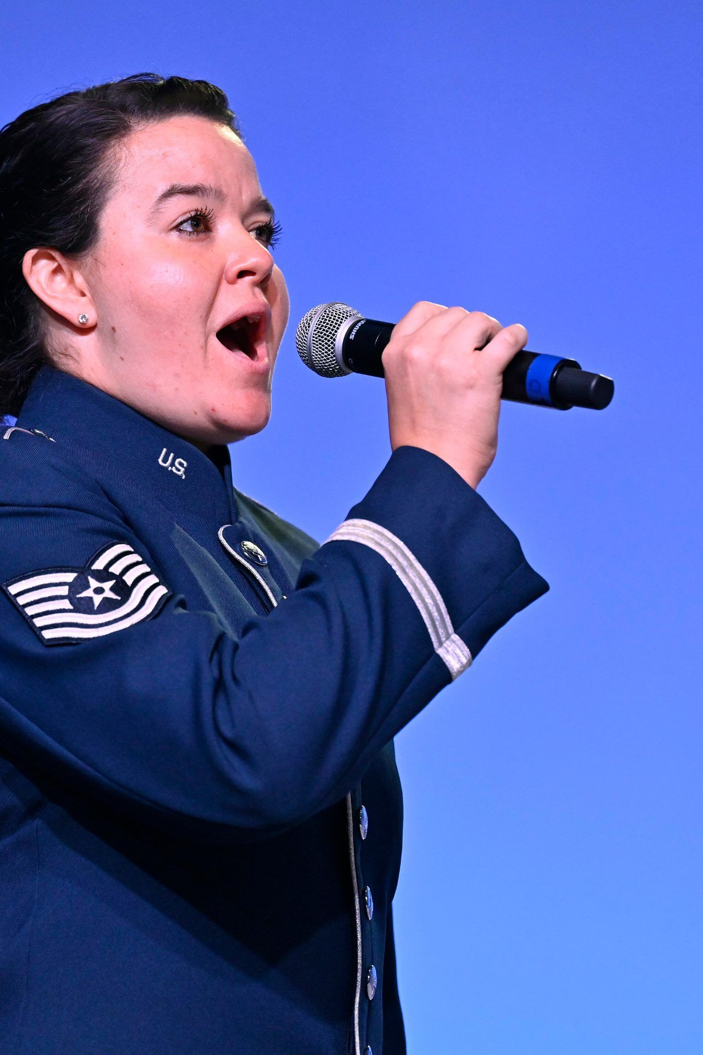 A United States Air Force vocalist singing the national anthem into a microphone