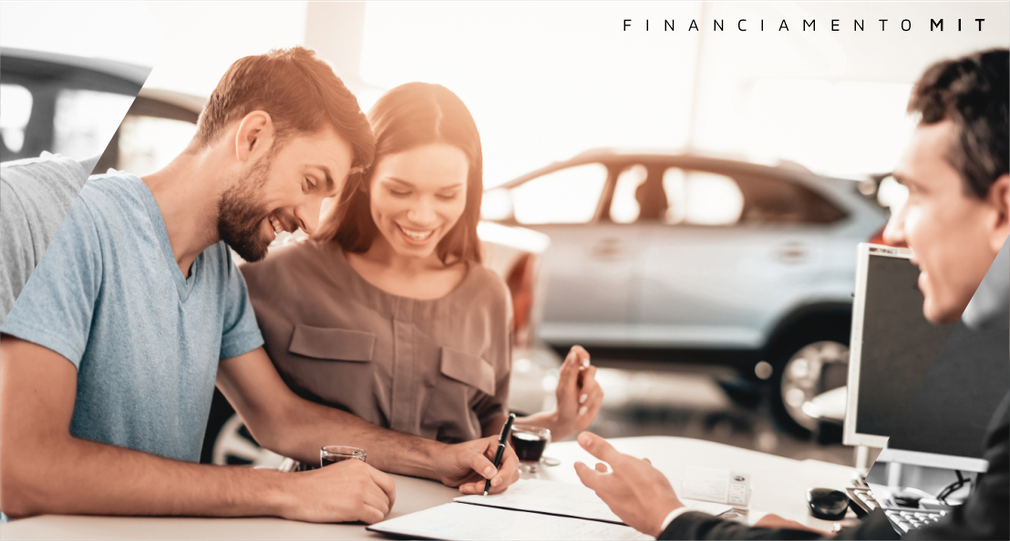 Um homem e uma mulher estão sentados à mesa assinando um contrato de financiamento