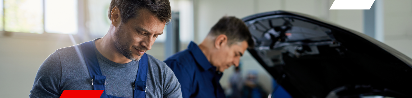 Dois mecânicos estão trabalhando em um carro em uma garagem.