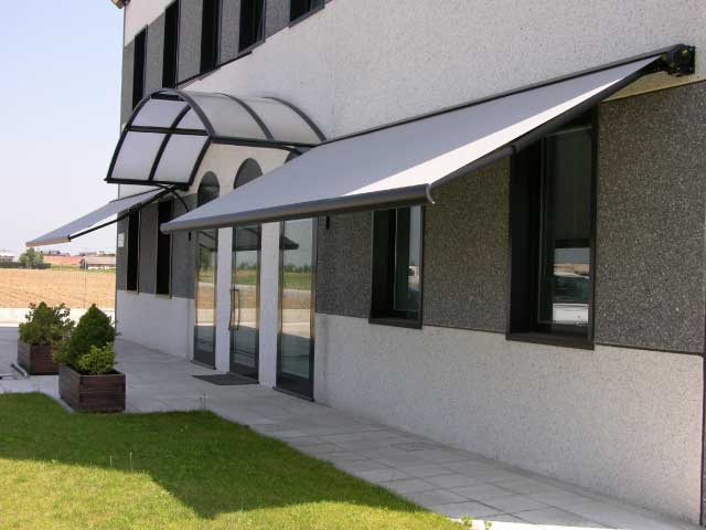 Esterno dell'edificio con una tenda grigia sopra porte e finestre in vetro.