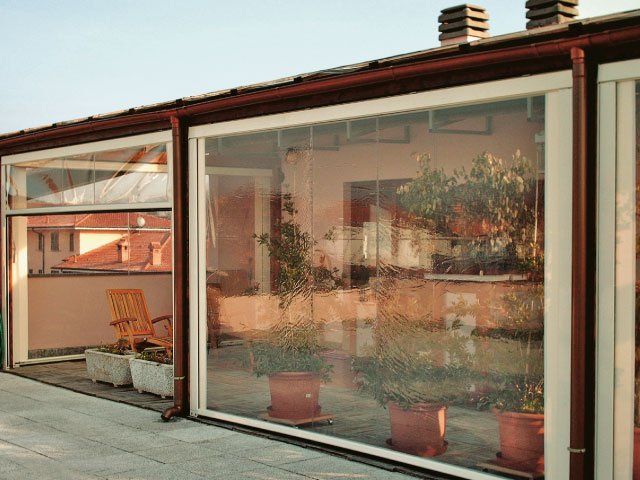 Un patio racchiuso da pannelli di plastica trasparente, con piante in vaso all'interno.