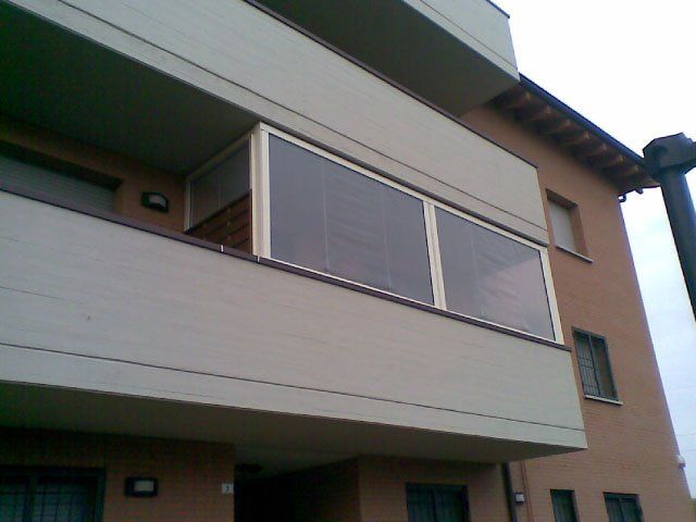 Balcone con finestre in vetro su un condominio beige.