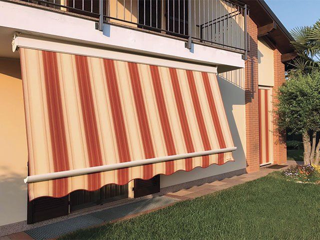 Tenda a strisce, marrone e beige, che si estende dal balcone di un edificio.