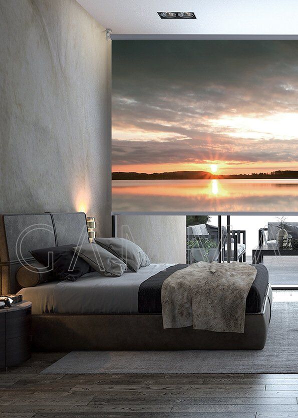 Camera da letto con ampia finestra che si affaccia sul tramonto sull'acqua. Pareti e biancheria da letto grigie.