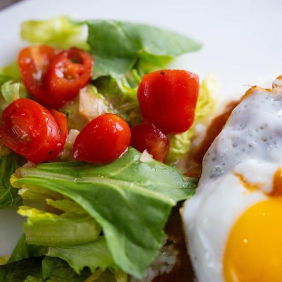 Fried egg with cherry tomatoes and leafy green salad on a plate