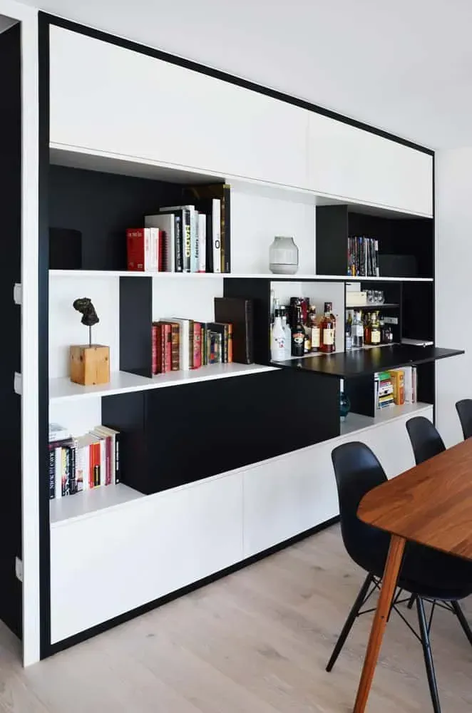 Modernes, schwarz-weißes Einbauregal im Esszimmer neben einem Holztisch und schwarzen Stühlen