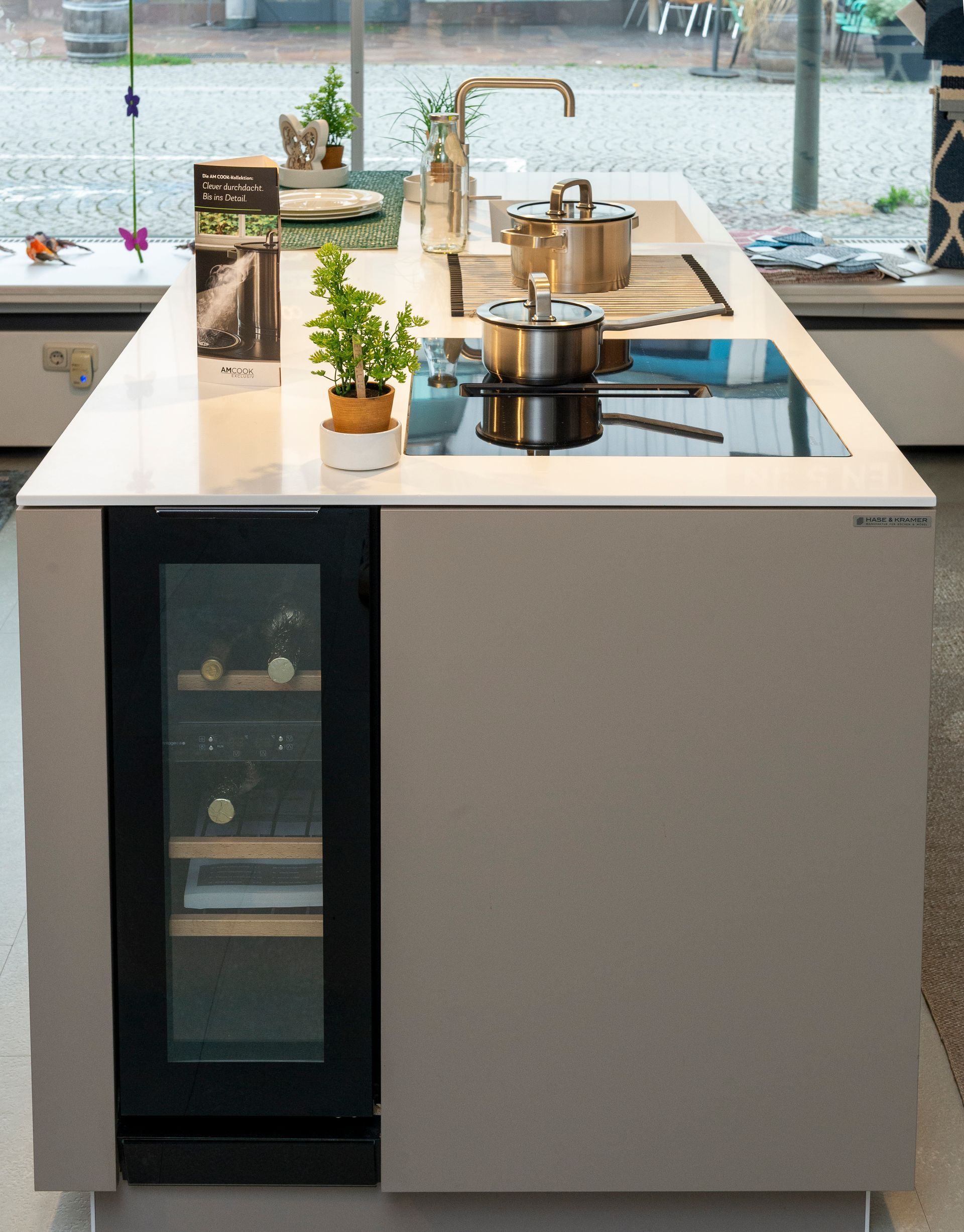 Schwarzer viertüriger Schrank mit quadratischem Griff, der in einem Büro oder Flur steht.