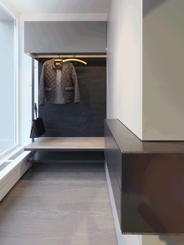 Kompakte Garderobennische mit einer gemusterten Jacke, die über einer Stufe und einem Regal in einem modernen Interieur hängt