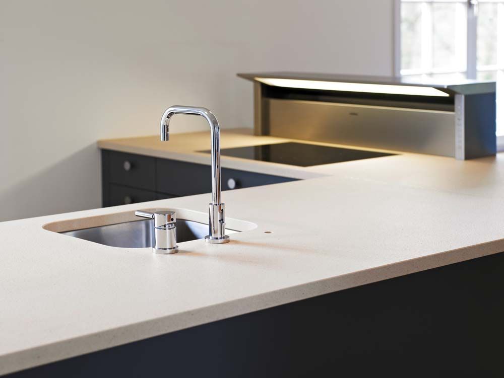 Moderne Küchenarbeitsplatte mit integriertem Spülbecken und Chromarmatur in einem minimalistischen Interieur