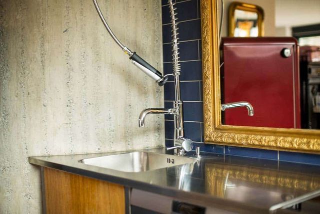 Modernes Badezimmerwaschbecken mit verchromter Armatur, rotem Spiegelschrank und strukturierter Wandgestaltung