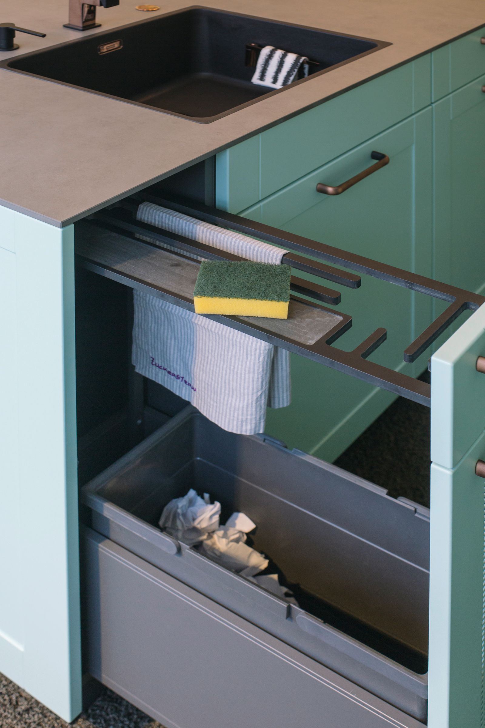Küchenschrank mit ausziehbaren Recyclingbehältern und Handtuchhalter unter einem Aufsatzwaschbecken