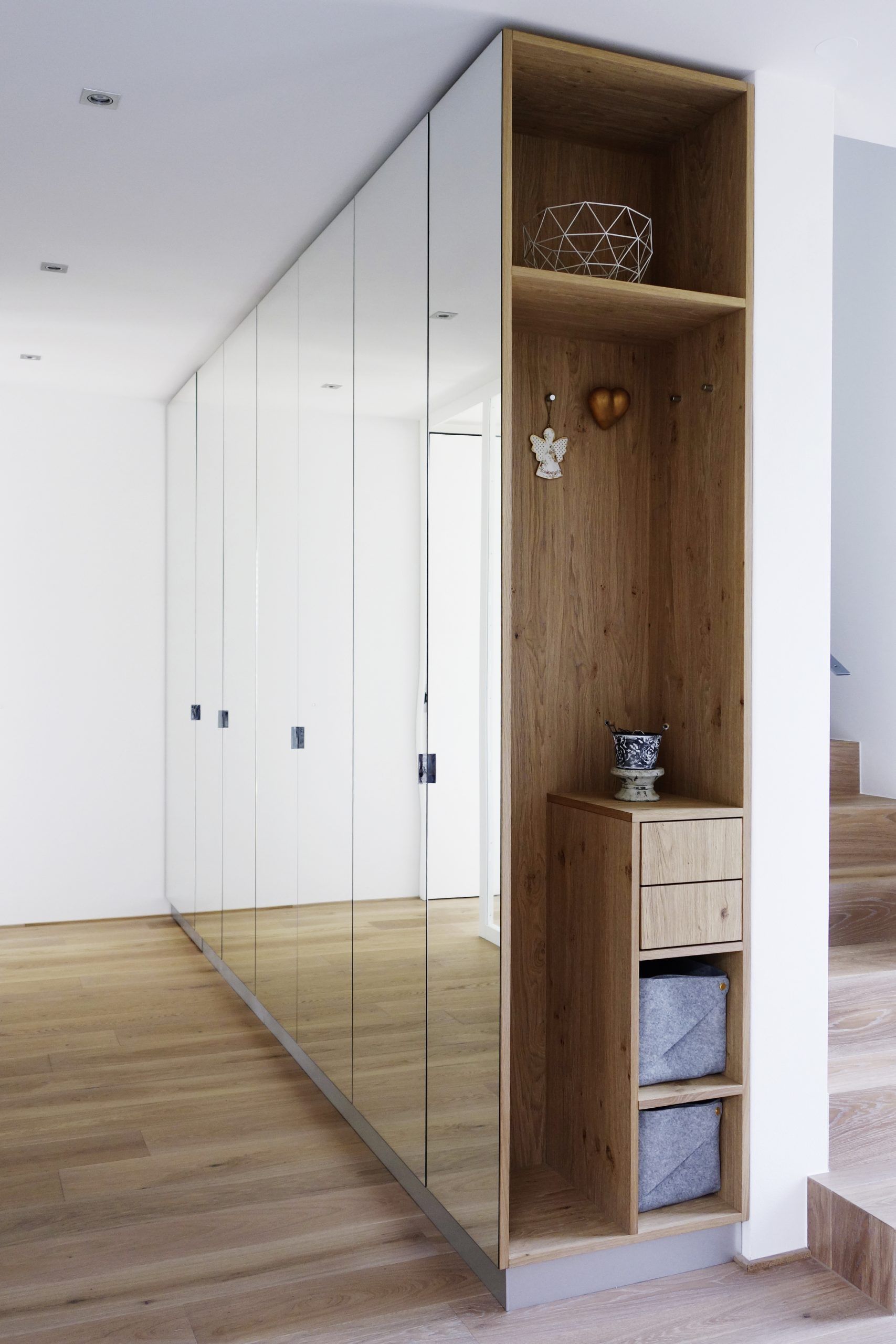 Moderner Flur mit weißen Spiegelschränken und einem Holzregal neben der Treppe