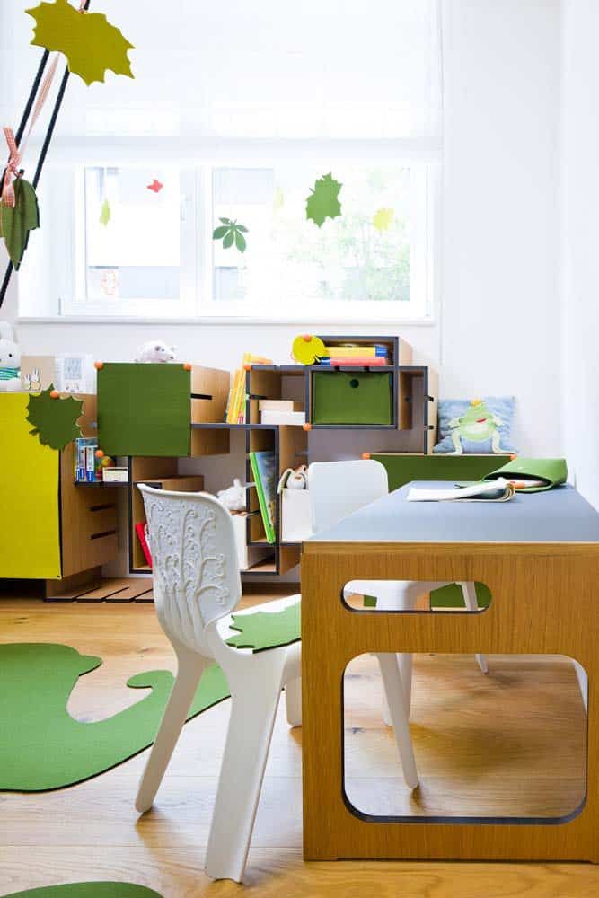 Helles Kinderklassenzimmer mit kleinen Tischen, Stühlen und Blätterdekorationen in einem sonnendurchfluteten Raum