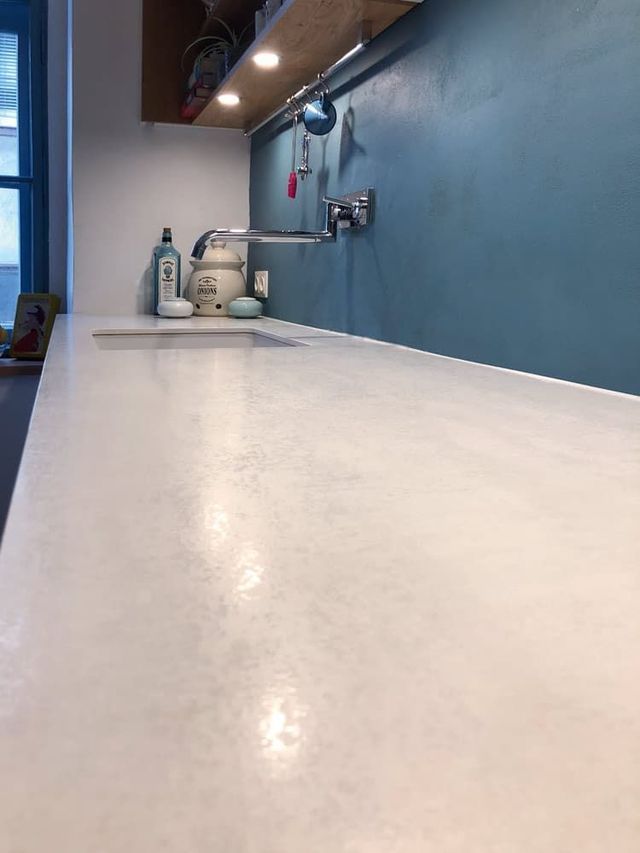 Badezimmer mit blauen Wänden, weißer Arbeitsplatte und Armatur, aus einer niedrigen Perspektive betrachtet.