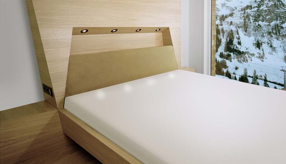 Modernes Schlafzimmer mit Bett, Holzkopfteil und Blick auf die verschneite Landschaft durch ein großes Fenster
