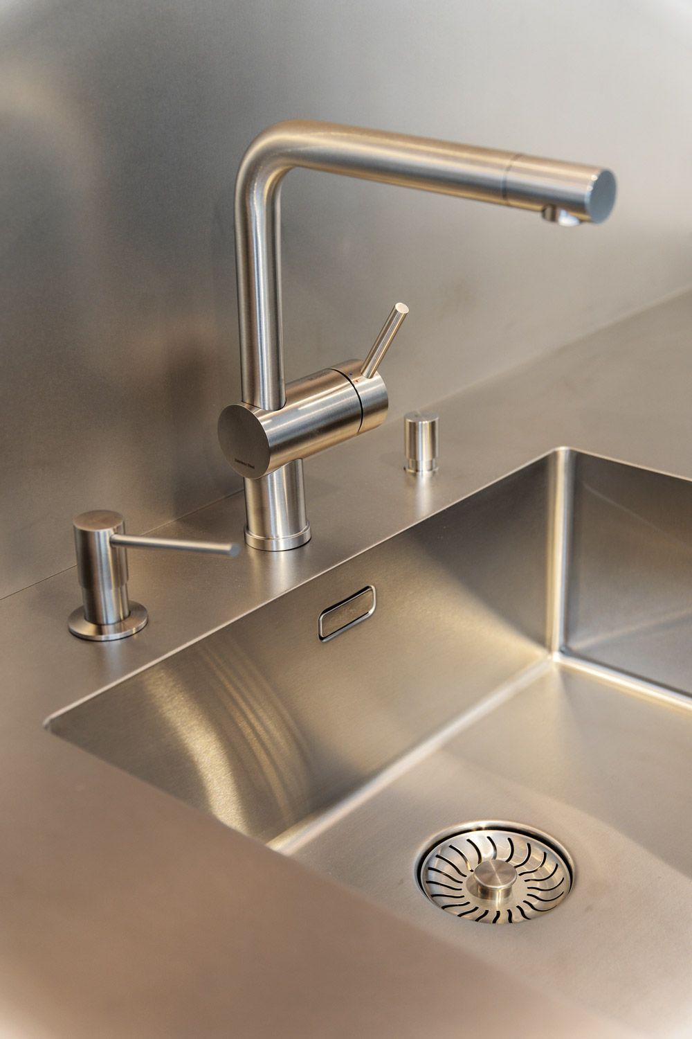 Küchenspüle aus Edelstahl mit moderner Armatur und Abfluss in einer minimalistischen Arbeitsplatte.