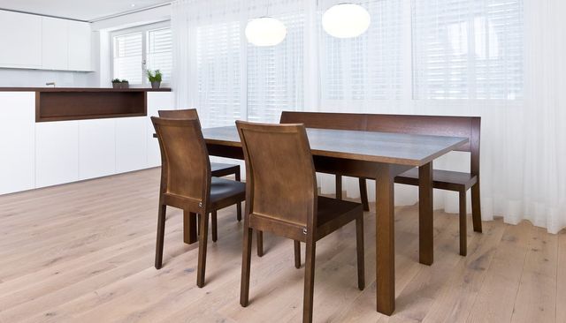 Modernes Esszimmer mit Holztisch und Stühlen neben einer hellen Küchentheke.