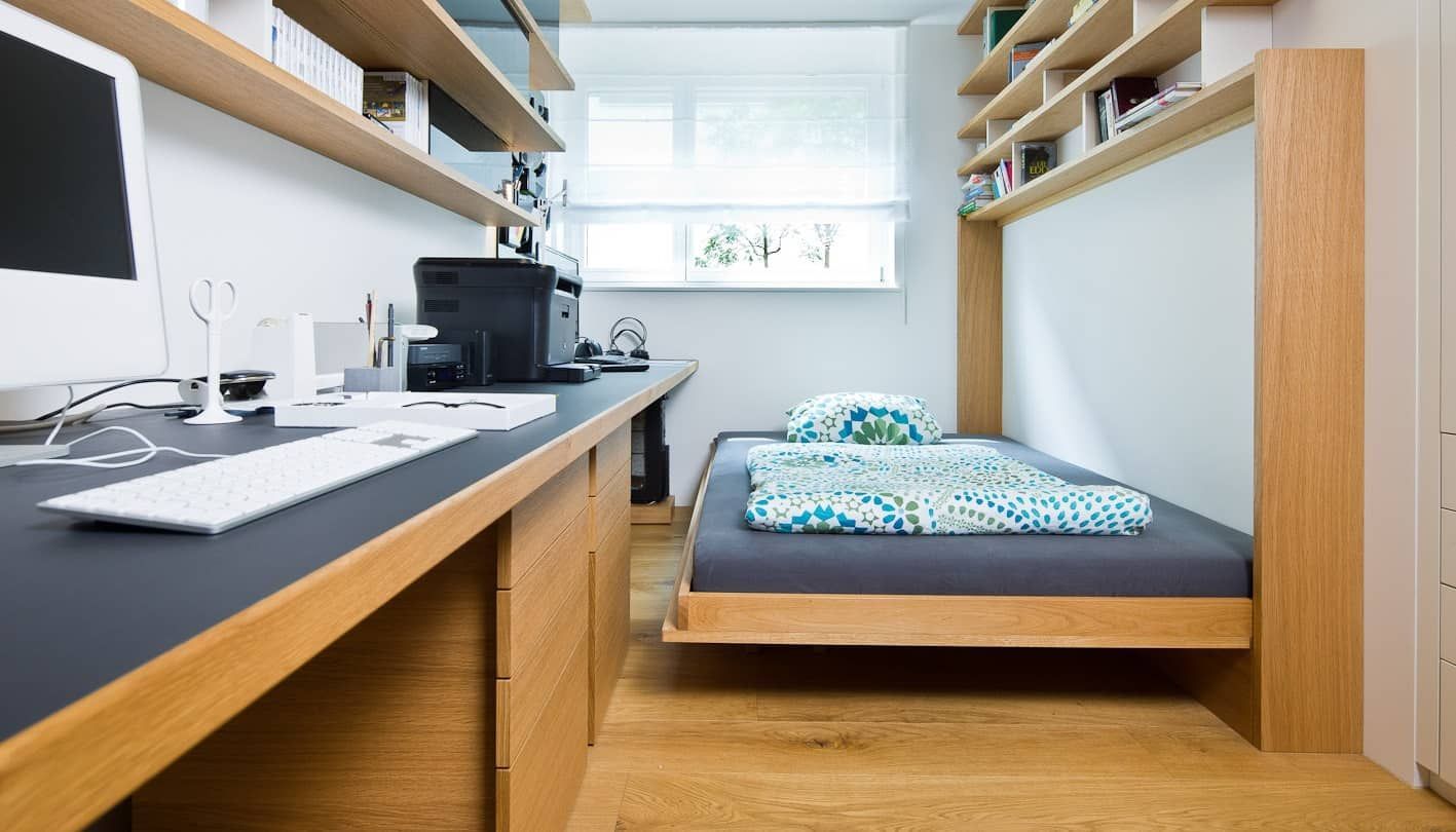 Kleines, modernes Schlafzimmer mit Einzelbett, Schreibtisch, Regalen und hellen Holzschränken.