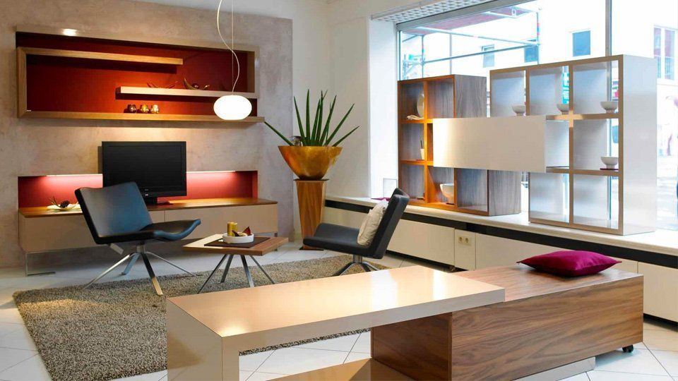 Modernes Wohnzimmer mit Sofa, Sessel, Couchtisch, Schreibtisch und großem Regal in der Nähe eines hellen Fensters