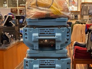 Two blue industrial HEPA air scrubbers stacked in a retail store, with a bag of hoses on top.
