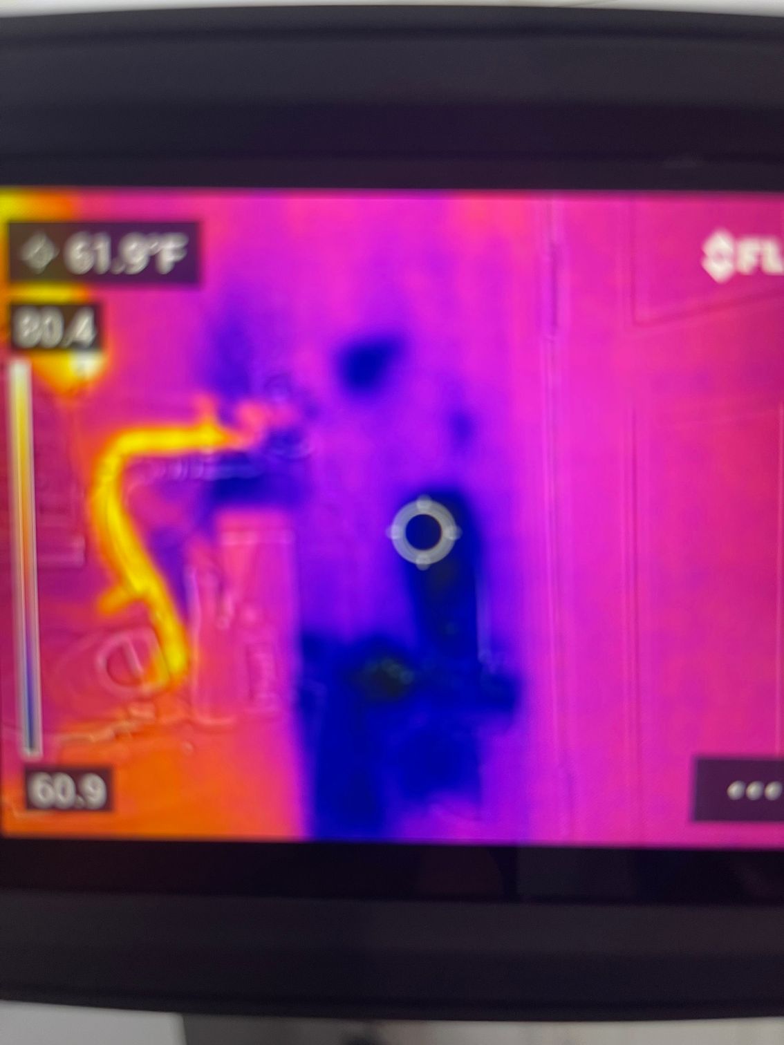 Thermal image showing cold air leaking around a doorway, indicated by blue and purple colors against a warmer wall.